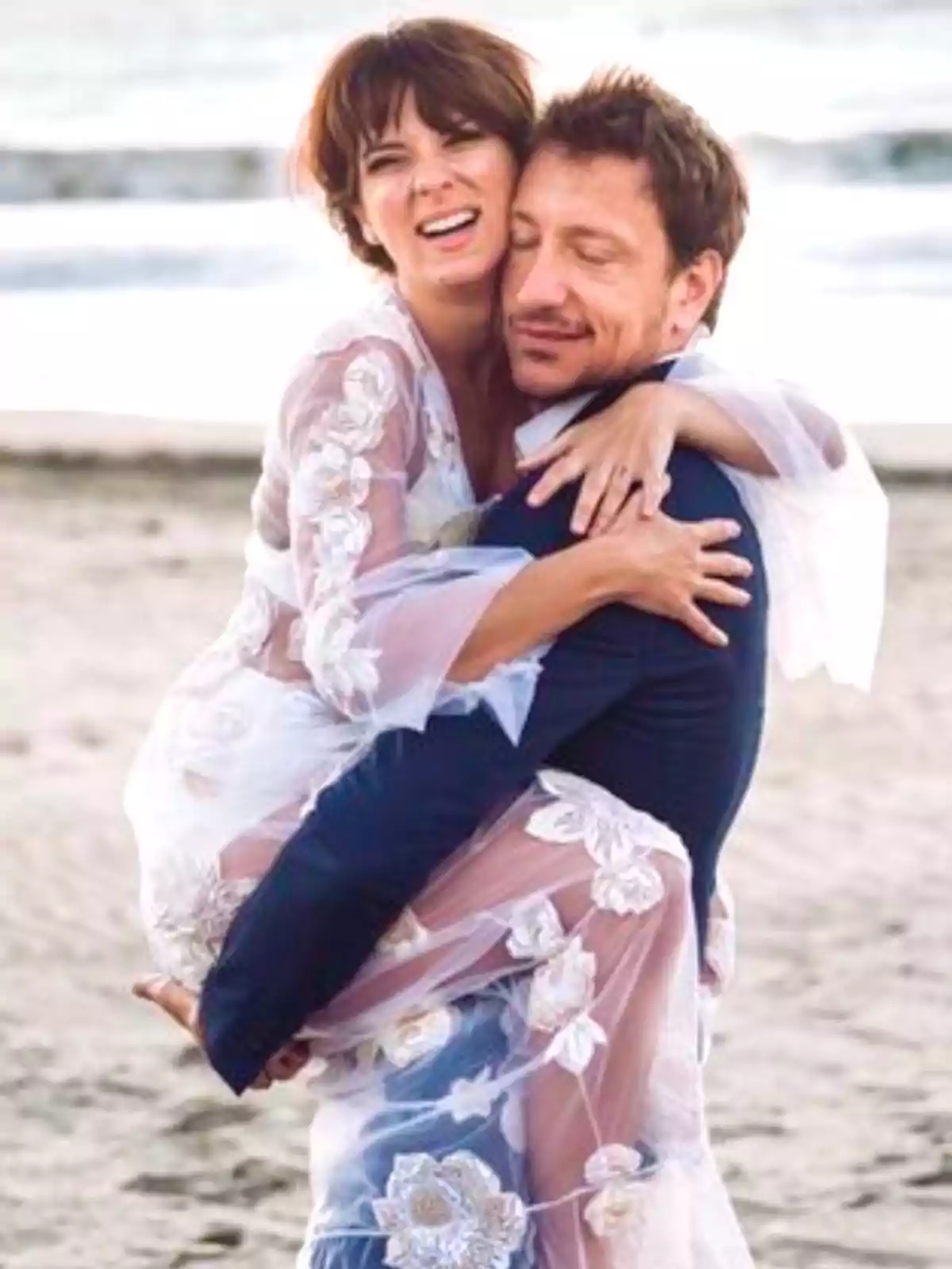 Couple hugging on the beach while smiling and enjoying the moment together Couple hugging on the beach while smiling and enjoying the moment together