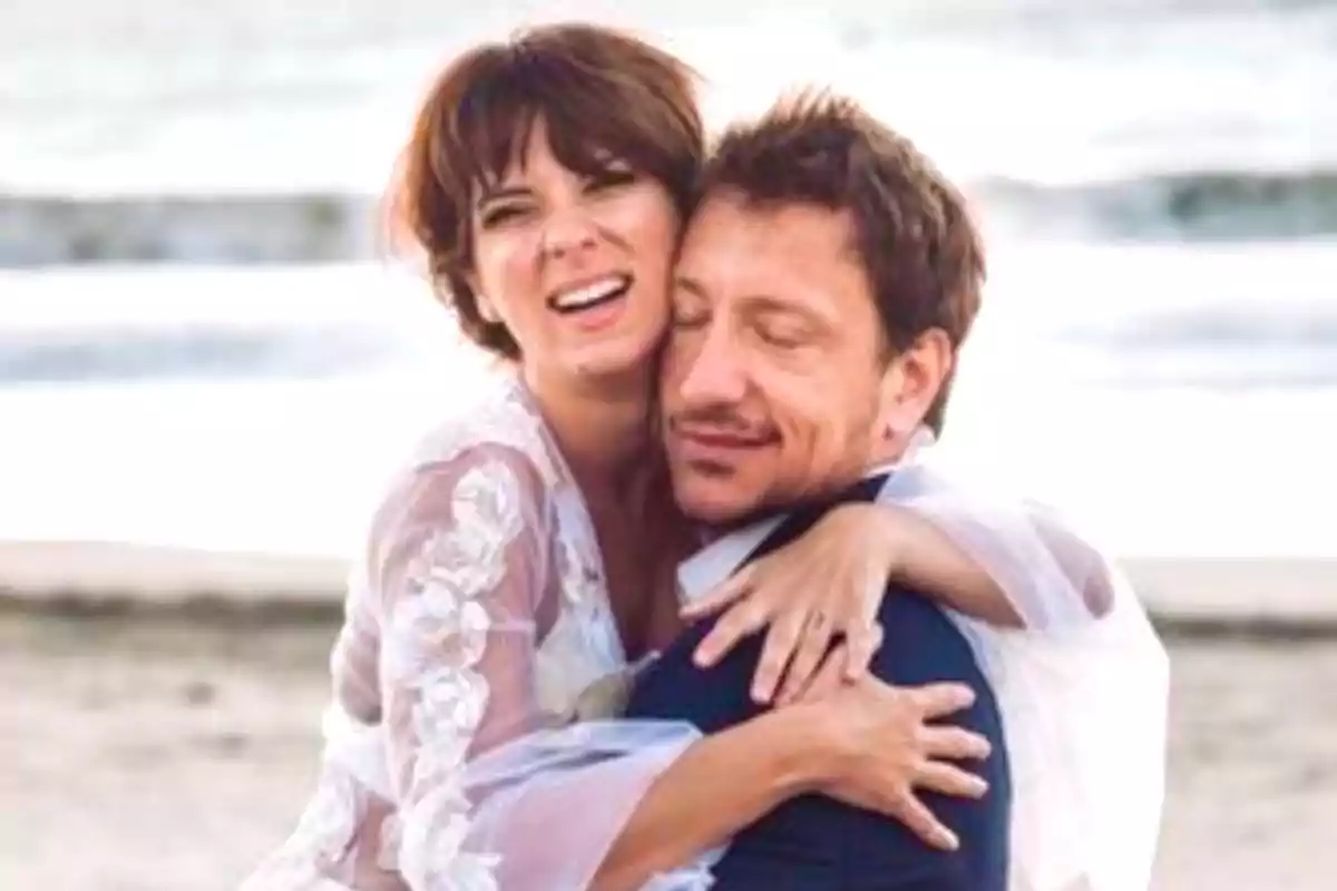Pareja abrazándose en la playa con expresiones de felicidad