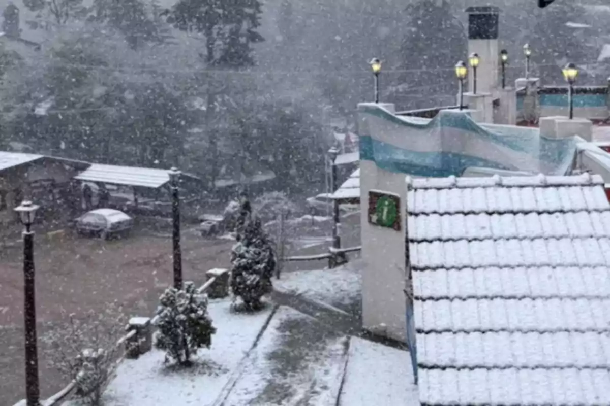 Vista de un pueblo cubierto de nieve con una bandera argentina ondeando y faroles encendidos durante una nevada intensa