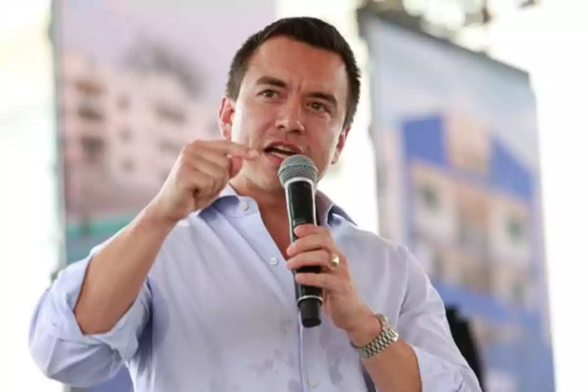 Short-haired man in a light blue jersey speaking in public while holding a microphone and gesturing with his hand Short-haired man in a light blue jersey speaking in public while holding a microphone and gesturing with his hand