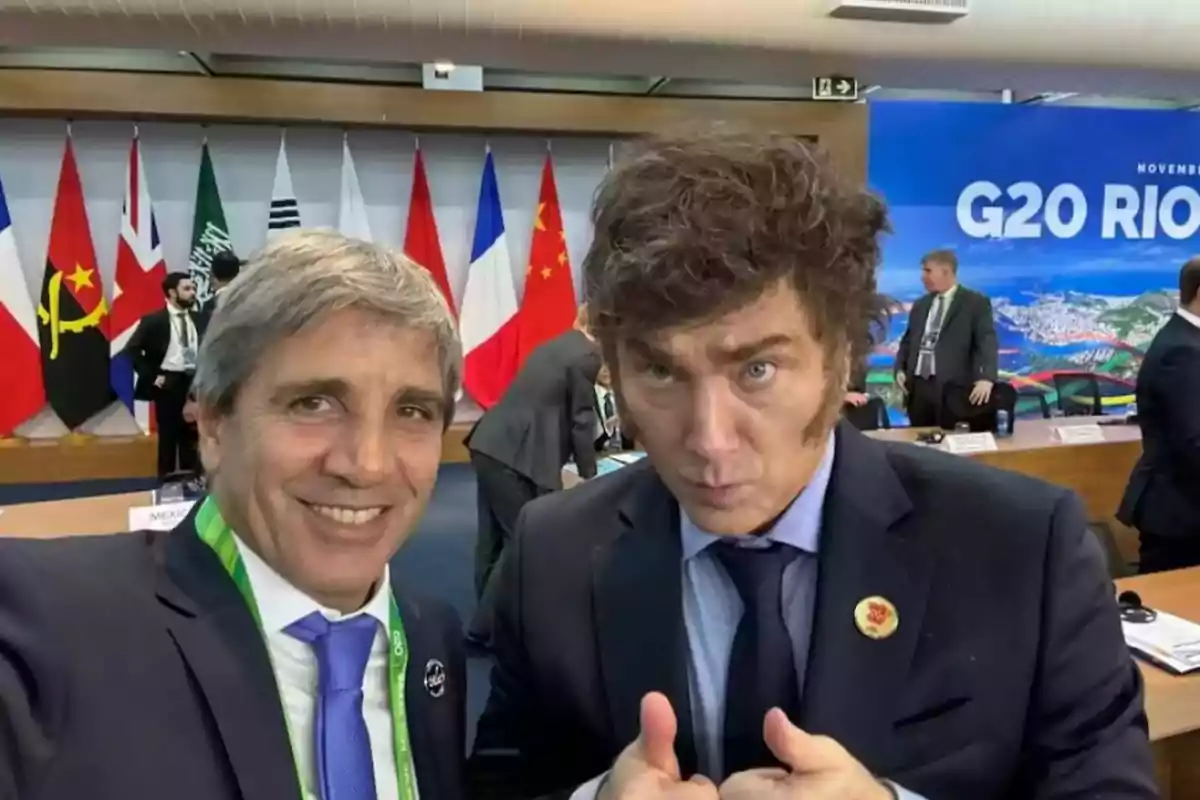 Dos hombres de traje posan para una selfie en una sala de conferencias con banderas de varios países y un cartel del G20 en el fondo Dos hombres de traje posan para una selfie en una sala de conferencias con banderas de varios países y un cartel del G20 en el fondo
