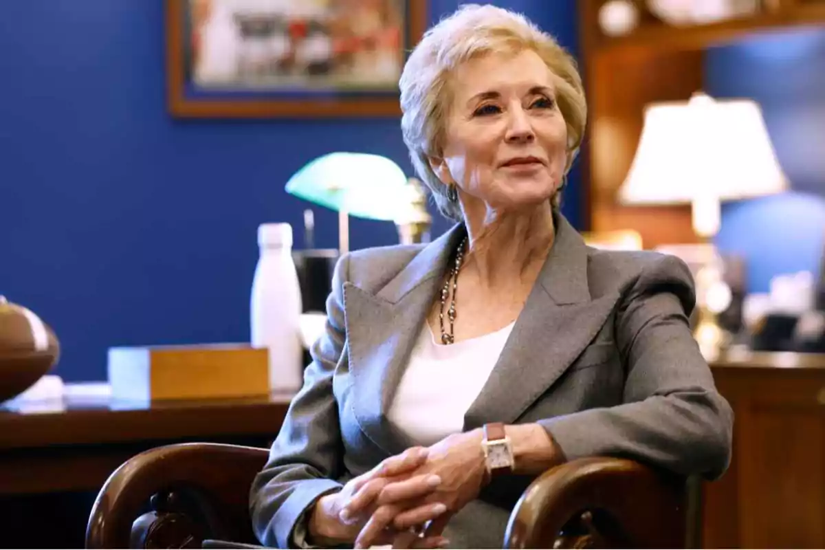 Older woman with short blonde hair sitting in an elegant office with a blue background and lit lamps Older woman with short blonde hair sitting in an elegant office with a blue background and lit lamps