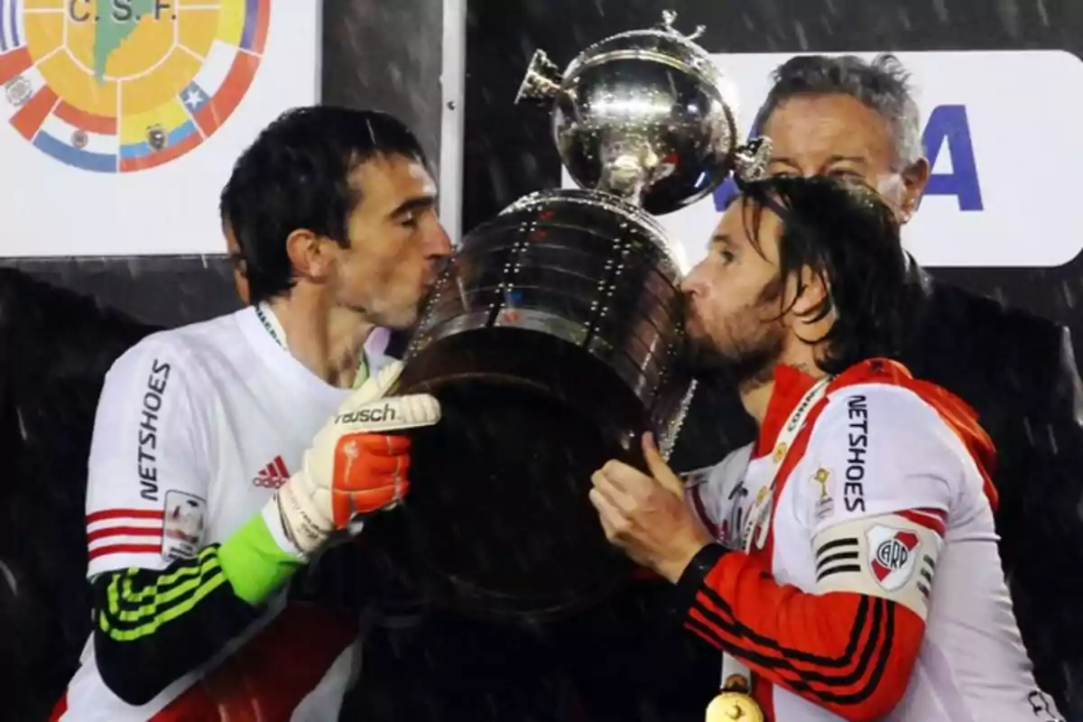 Dos futbolistas de River Plate besan el trofeo de la Copa Libertadores durante una celebración bajo la lluvia Dos futbolistas de River Plate besan el trofeo de la Copa Libertadores durante una celebración bajo la lluvia