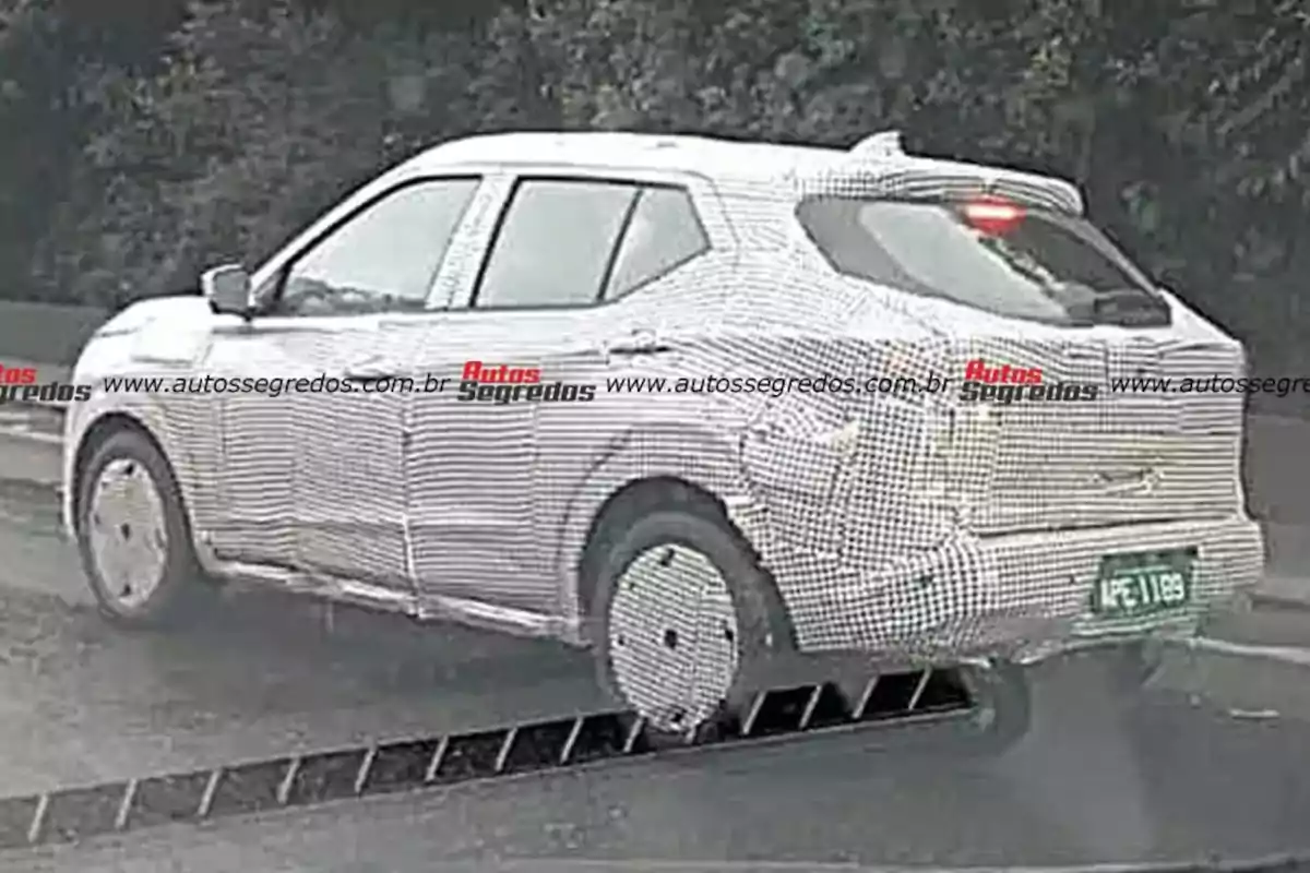 SUV vehicle covered with test camouflage driving on a wet road SUV vehicle covered with test camouflage driving on a wet road