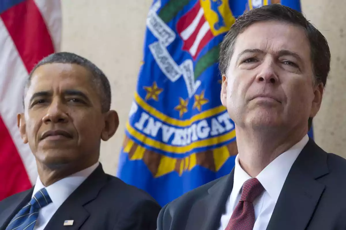 Two men in suits pose in front of official United States and FBI flags.