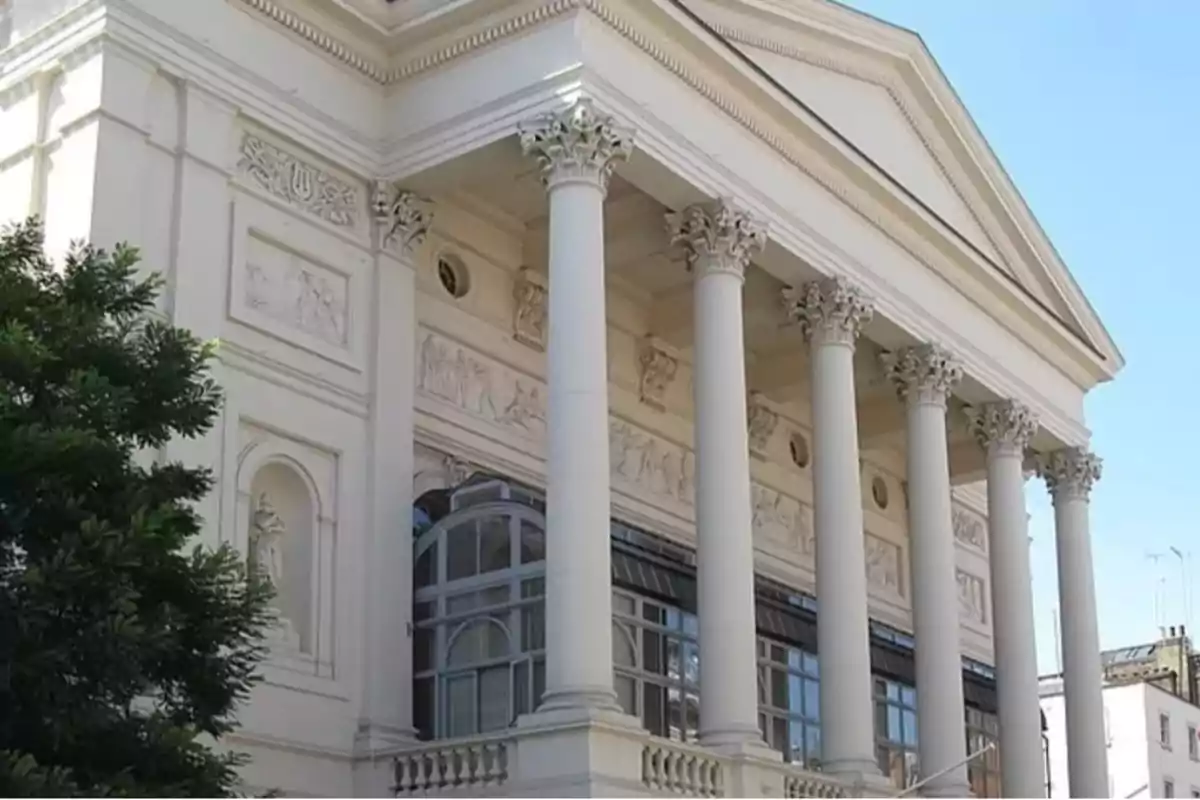 Fachada de un edificio clásico con columnas y relieves decorativos en la parte superior Fachada de un edificio clásico con columnas y relieves decorativos en la parte superior