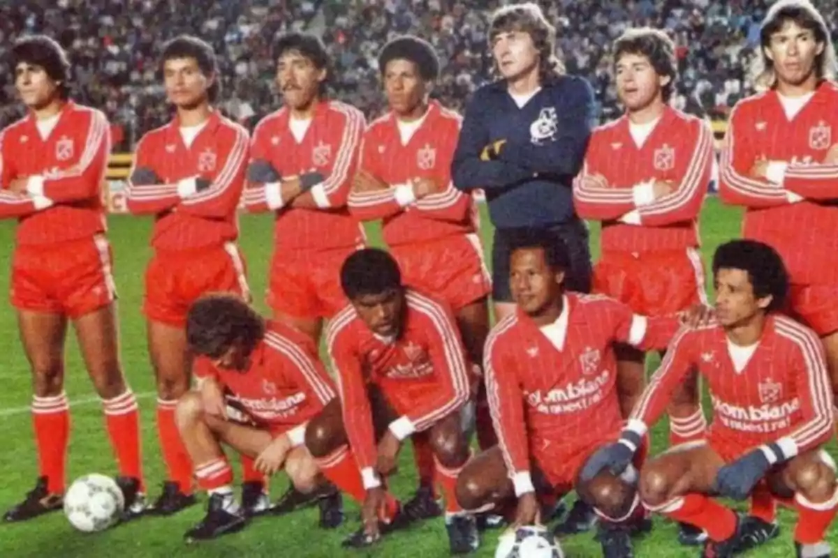 Soccer team posing on the field in red uniforms with white details before a match Soccer team posing on the field in red uniforms with white details before a match