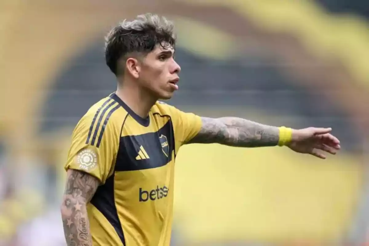Futbolista con uniforme amarillo y negro señalando con el brazo extendido durante un partido
