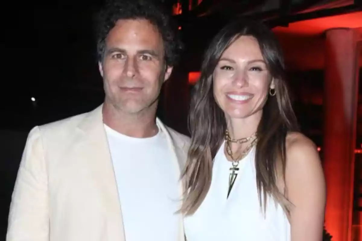 Pareja sonriendo y posando juntos en un evento nocturno con iluminación cálida de fondo