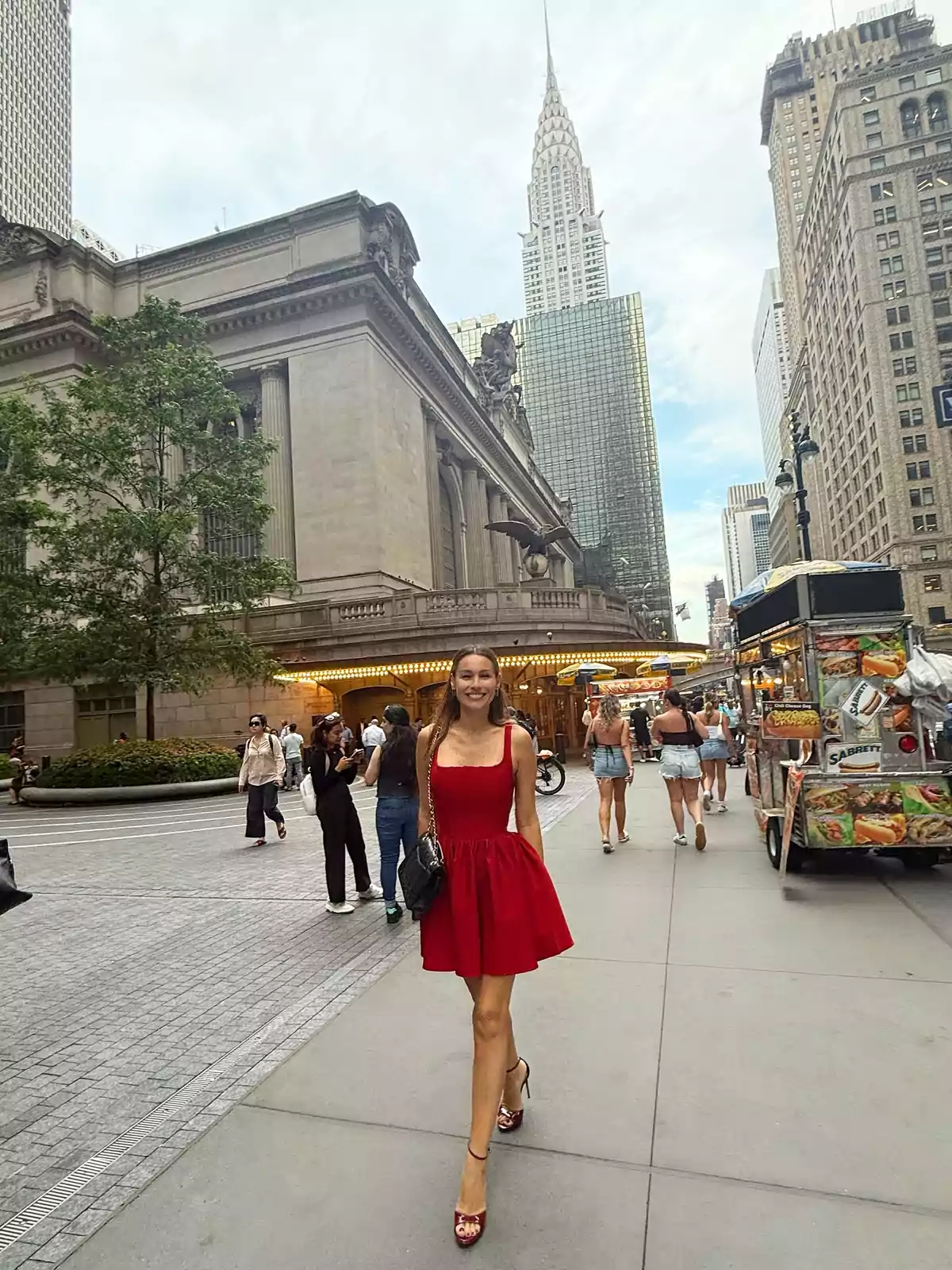 Woman in a red dress walking down a New York street in front of Grand Central Station with the Chrysler Building in the background Woman in a red dress walking down a New York street in front of Grand Central Station with the Chrysler Building in the background