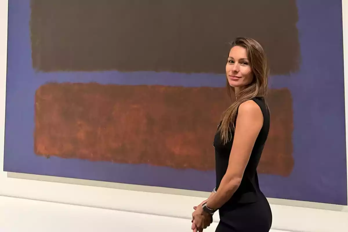 Woman with long hair and a black dress posing in front of an abstract painting with brown and blue color blocks in an art gallery Woman with long hair and a black dress posing in front of an abstract painting with brown and blue color blocks in an art gallery