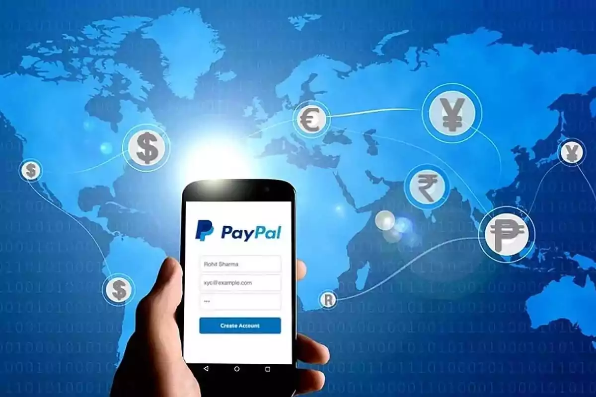 Person holding a mobile phone with the PayPal login screen in front of a blue world map with symbols of different currencies connected by digital lines Person holding a mobile phone with the PayPal login screen in front of a blue world map with symbols of different currencies connected by digital lines
