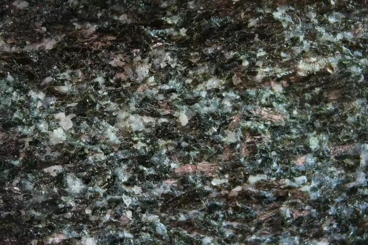 Granite surface with a speckled texture in dark tones and light flecks Granite surface with a speckled texture in dark tones and light flecks