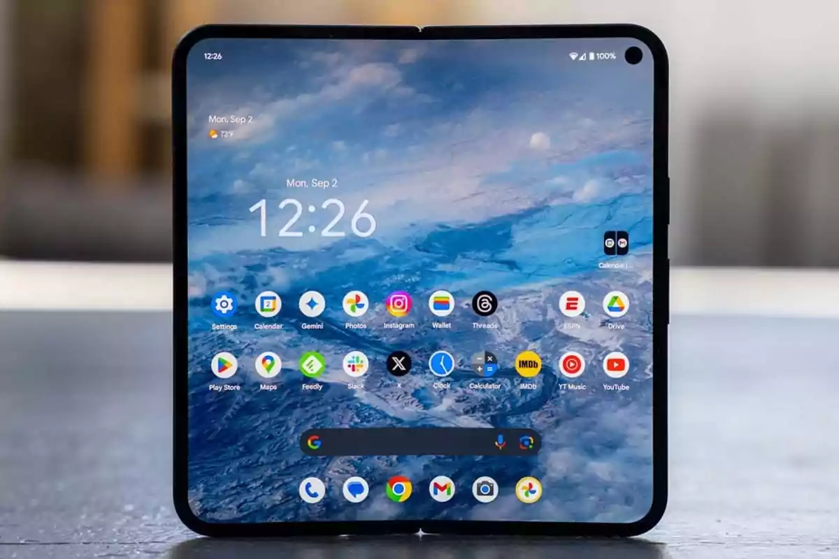 Foldable phone open showing the main screen with several apps and a blue landscape wallpaper Foldable phone open showing the main screen with several apps and a blue landscape wallpaper