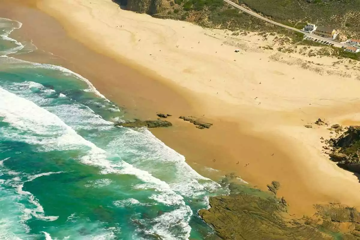 Aerial view of a golden sand beach with waves breaking on the shore and rock formations near the sea Aerial view of a golden sand beach with waves breaking on the shore and rock formations near the sea