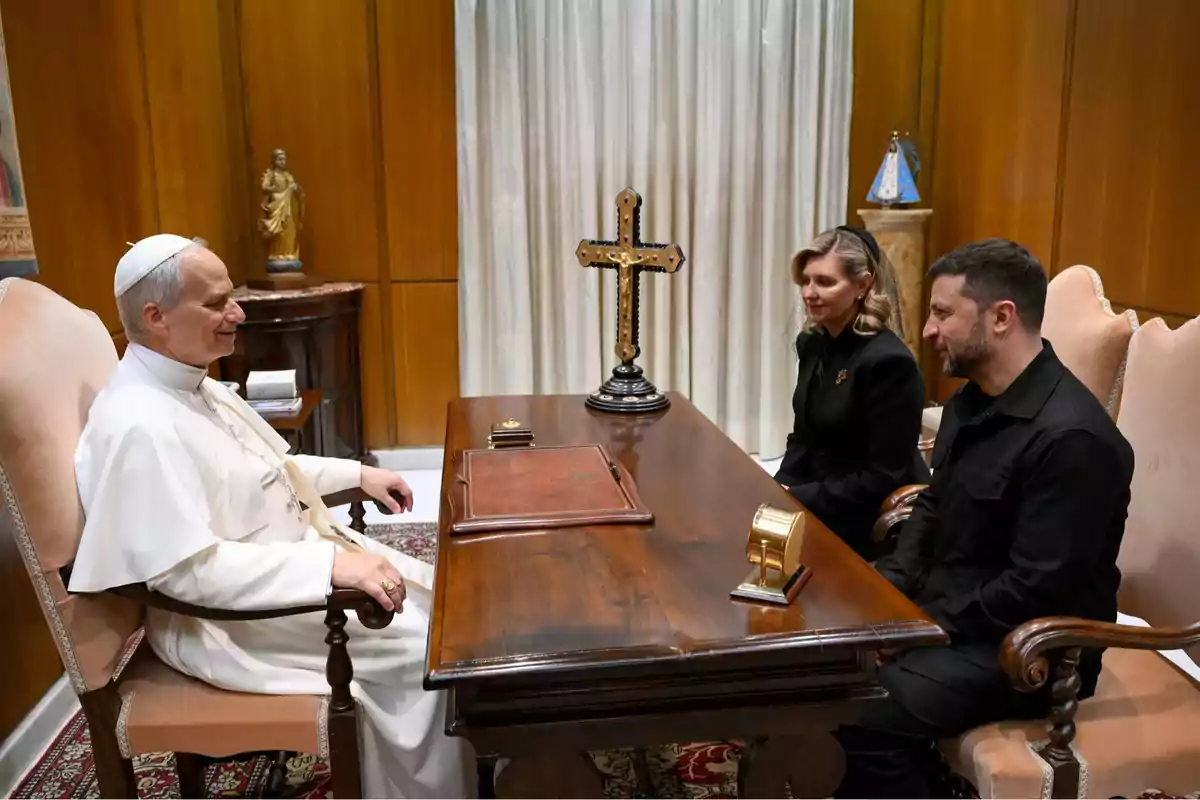 Tres personas sentadas en una reunión formal en una oficina elegante con una gran cruz sobre la mesa Tres personas sentadas en una reunión formal en una oficina elegante con una gran cruz sobre la mesa