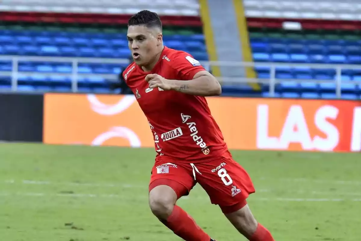 Soccer player in a red uniform running in a stadium during a match Soccer player in a red uniform running in a stadium during a match