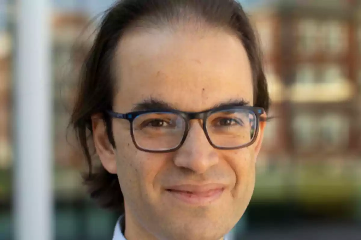 Hombre joven con gafas y cabello oscuro mirando a la cámara con una ligera sonrisa Hombre joven con gafas y cabello oscuro mirando a la cámara con una ligera sonrisa
