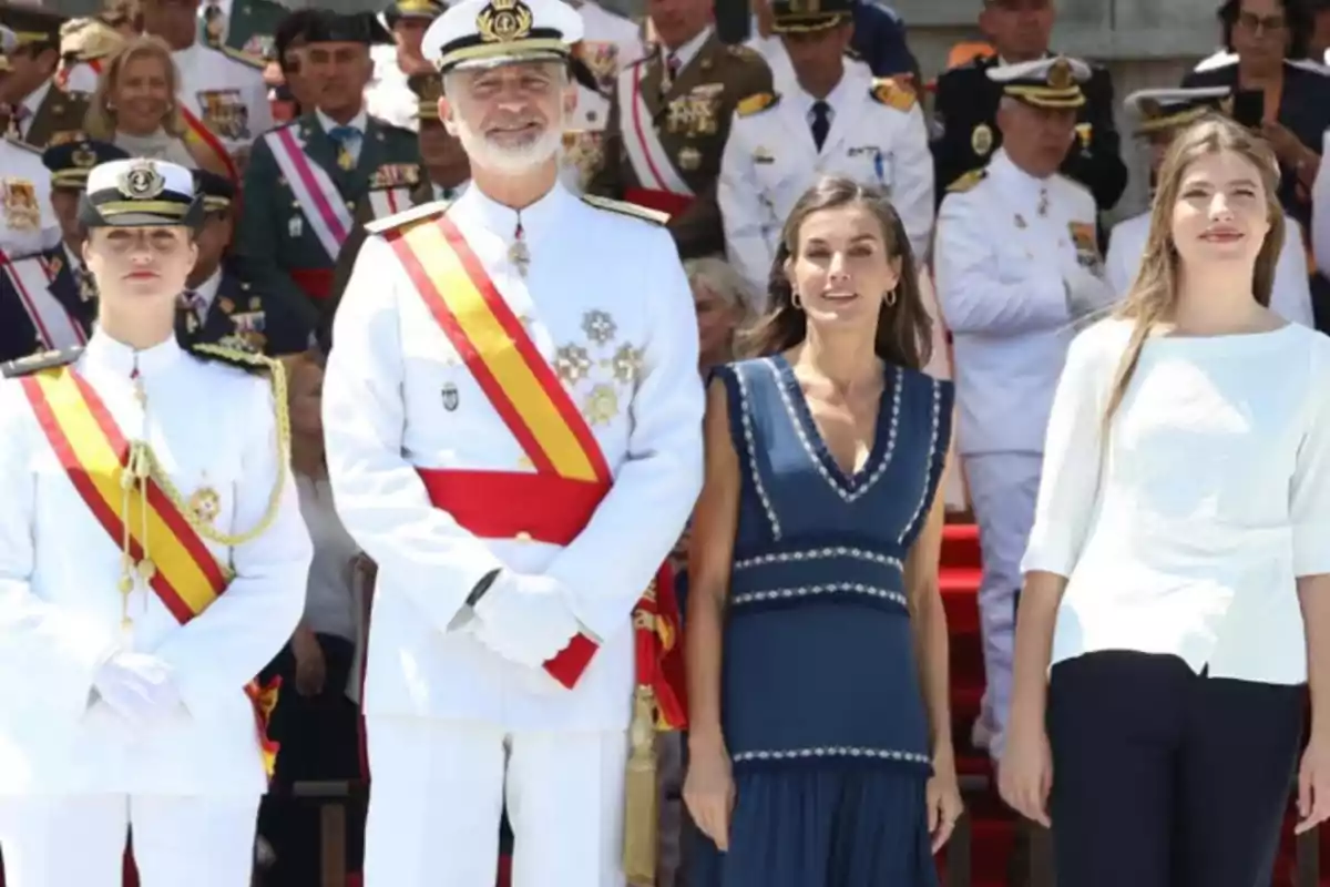 Four people pose at an official event surrounded by military personnel in dress uniforms. Four people pose at an official event surrounded by military personnel in dress uniforms.