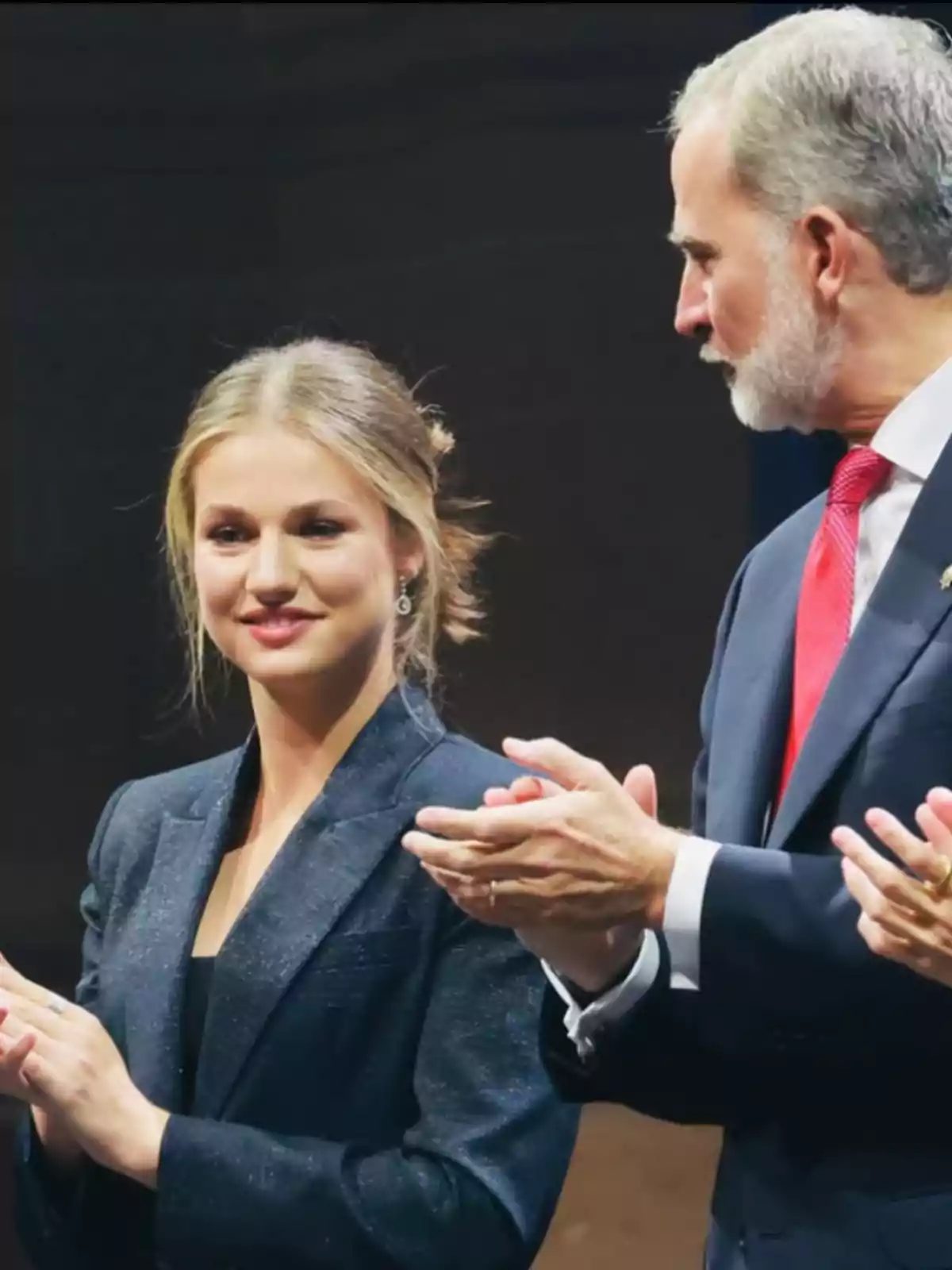 Dos personas elegantemente vestidas aplauden en un evento formal Dos personas elegantemente vestidas aplauden en un evento formal