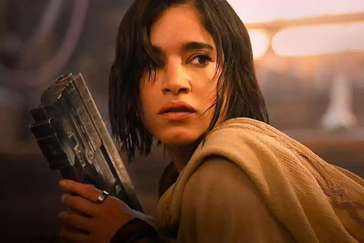 Short-haired, dark-haired woman holds a large weapon while looking to the side with a serious expression in a science fiction setting. Short-haired, dark-haired woman holds a large weapon while looking to the side with a serious expression in a science fiction setting.