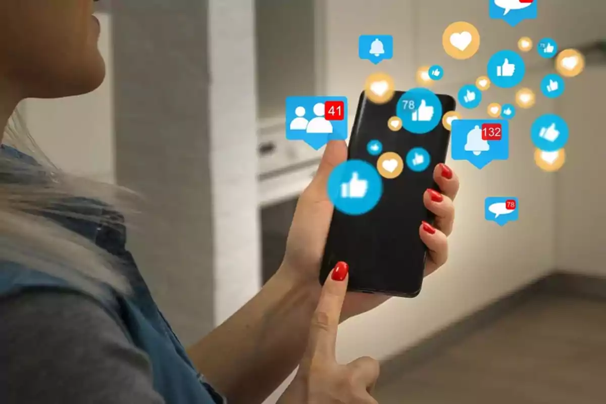 Persona usando un teléfono móvil con notificaciones y reacciones de redes sociales flotando alrededor de la pantalla Persona usando un teléfono móvil con notificaciones y reacciones de redes sociales flotando alrededor de la pantalla