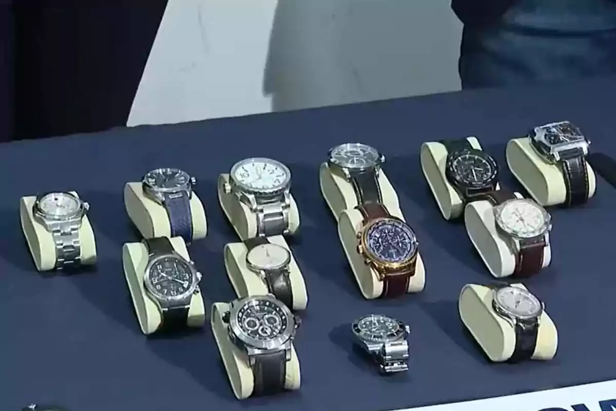 Several wristwatches of different styles and bands displayed on a blue table Several wristwatches of different styles and bands displayed on a blue table