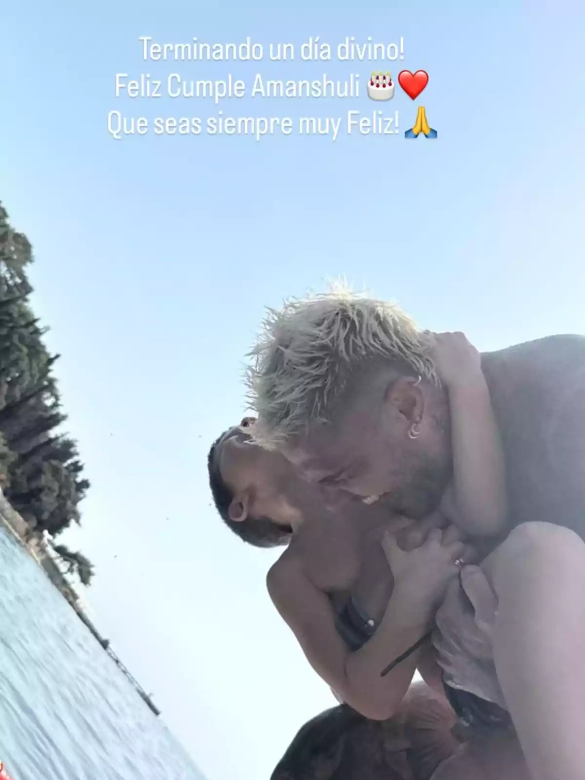 Persona rubia abrazando y jugando con un niño pequeño en la orilla de un lago en un día soleado, ambos sonríen y se ven felices Persona rubia abrazando y jugando con un niño pequeño en la orilla de un lago en un día soleado, ambos sonríen y se ven felices