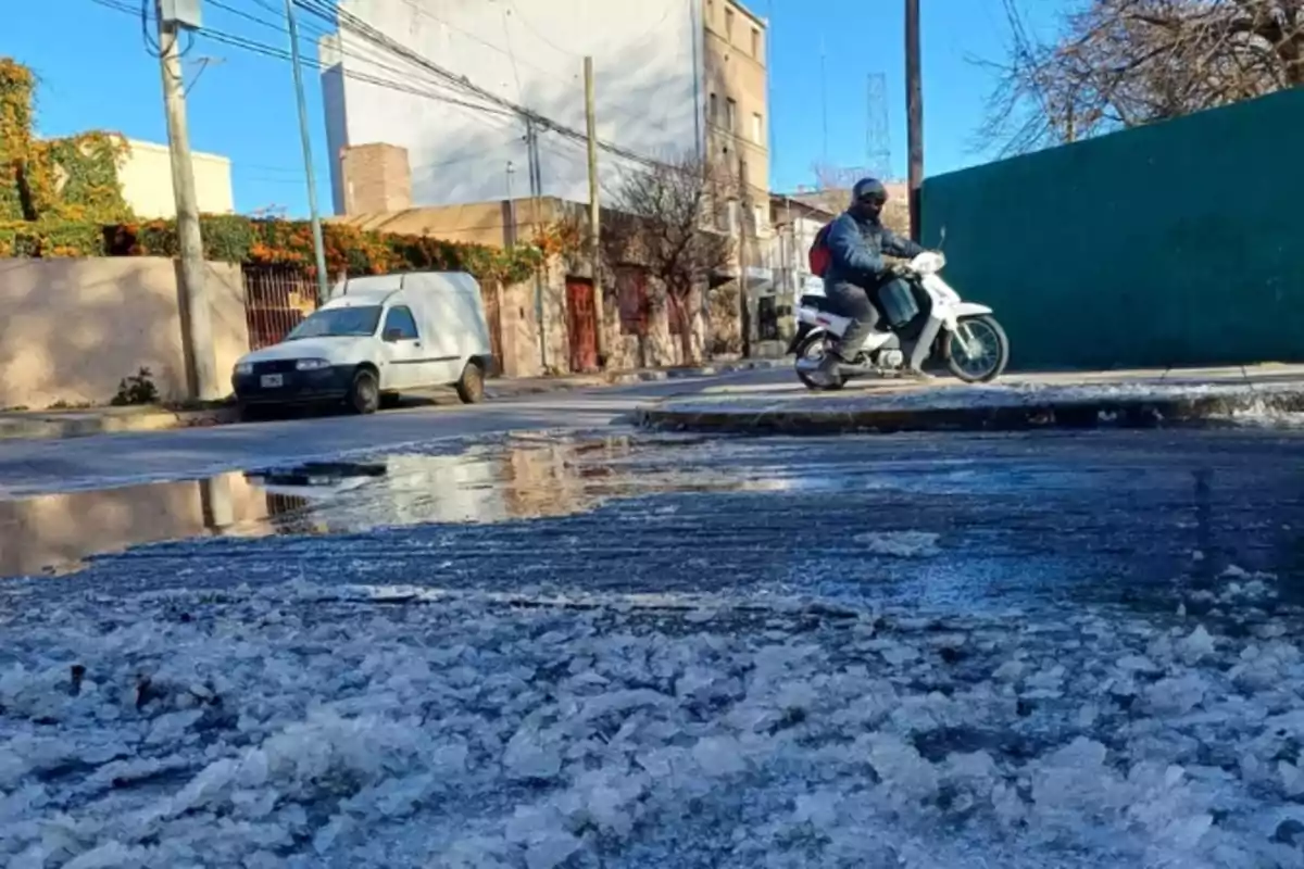 A street with ice on the asphalt, a man on a motorcycle, and a parked truck in the background on a sunny day A street with ice on the asphalt, a man on a motorcycle, and a parked truck in the background on a sunny day