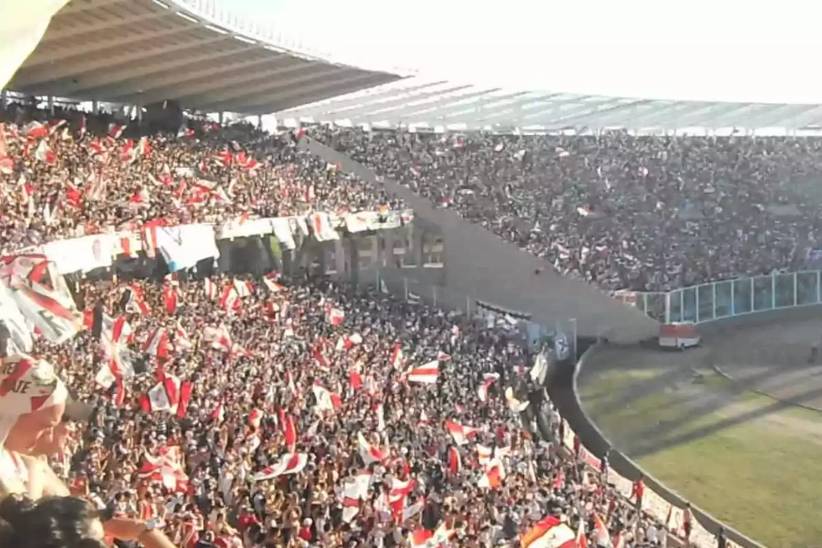 Stadium full of fans cheering with red and white flags during a soccer match