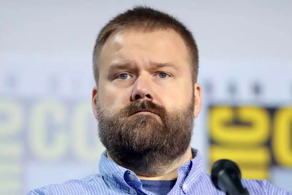 Man with a beard and short hair with a serious expression in front of a microphone and a blurred background Man with a beard and short hair with a serious expression in front of a microphone and a blurred background
