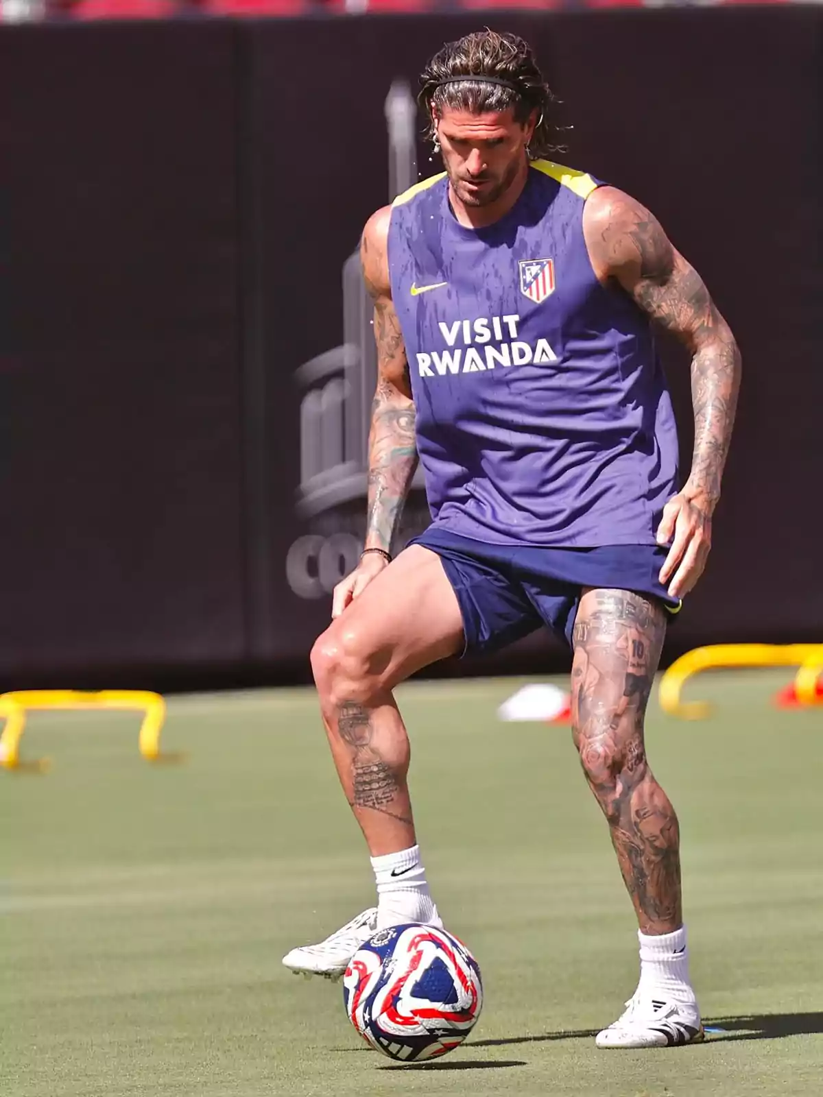 Soccer player in Atlético de Madrid training kit controlling a ball on a grass field Soccer player in Atlético de Madrid training kit controlling a ball on a grass field