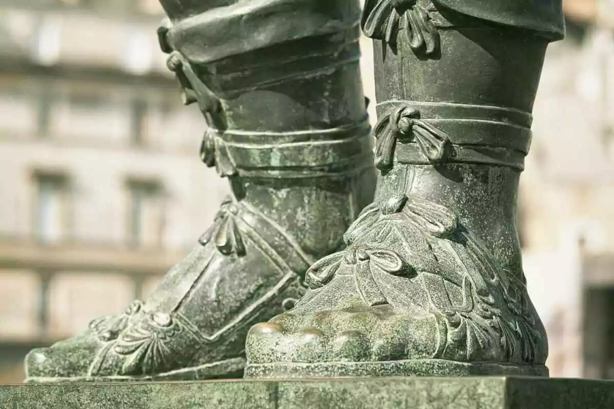 Detalle de los pies de una estatua de bronce con sandalias decoradas Detalle de los pies de una estatua de bronce con sandalias decoradas