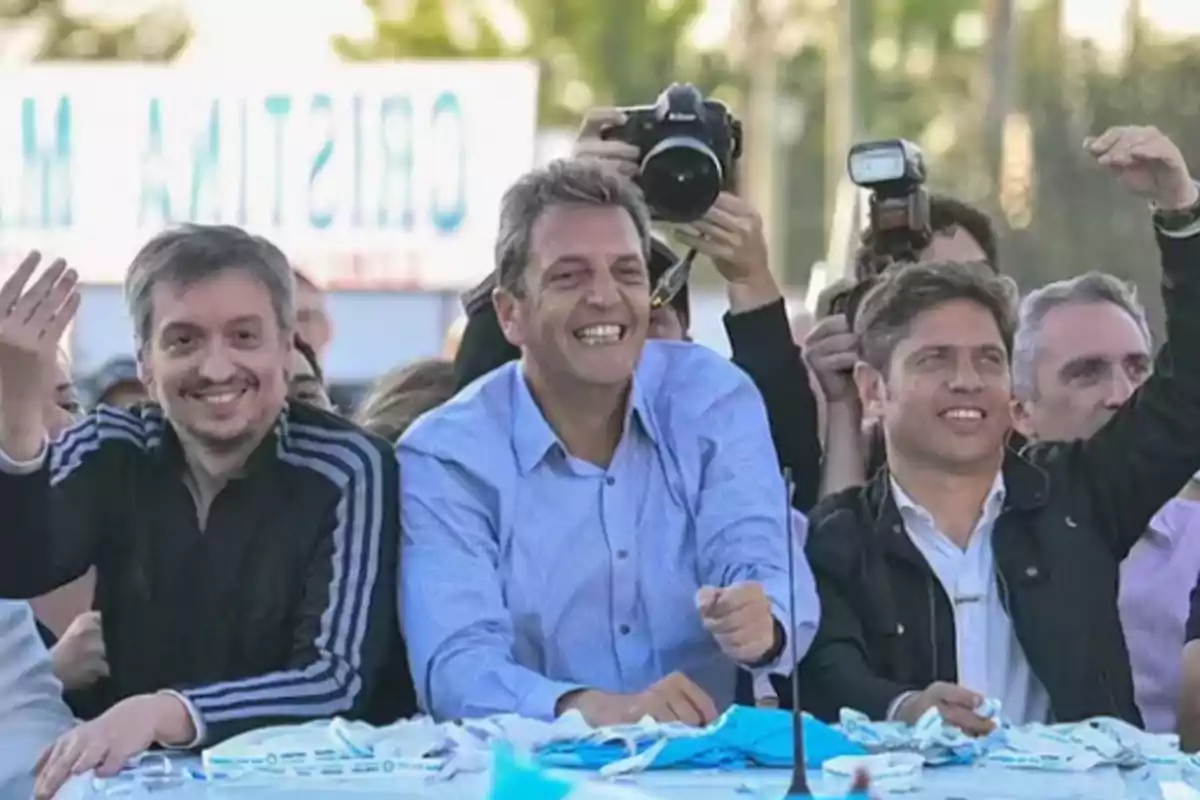 Three men smile and wave at a public outdoor event surrounded by photographers and people. Three men smile and wave at a public outdoor event surrounded by photographers and people.