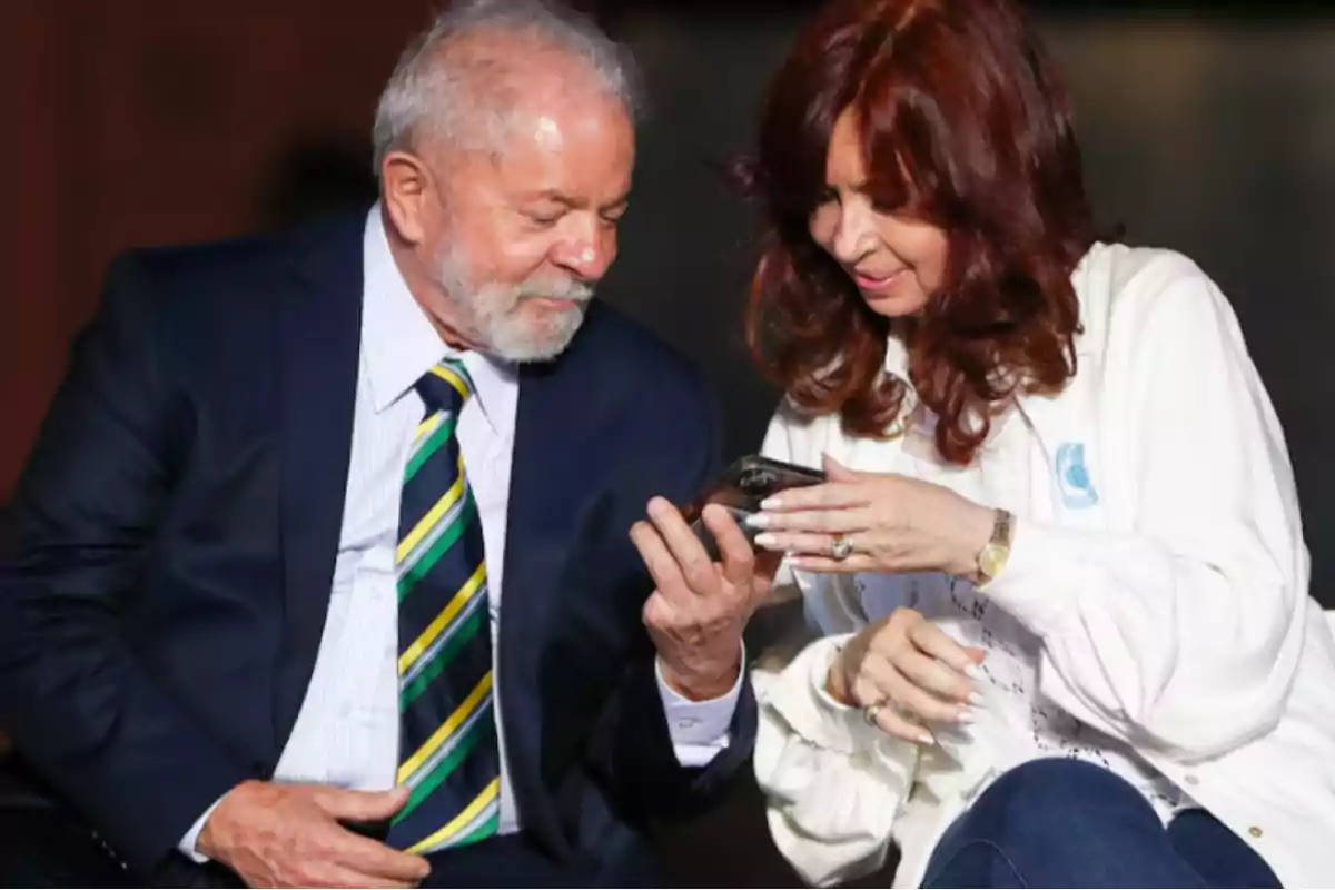 Two people sit together watching a mobile phone screen while smiling. Two people sit together watching a mobile phone screen while smiling.