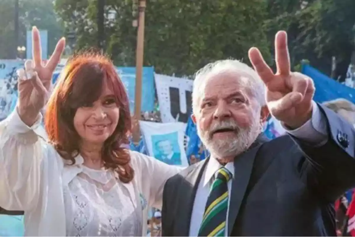 Two people smile and make the victory sign with their fingers while outdoors at an event with flags and banners in the background. Two people smile and make the victory sign with their fingers while outdoors at an event with flags and banners in the background.