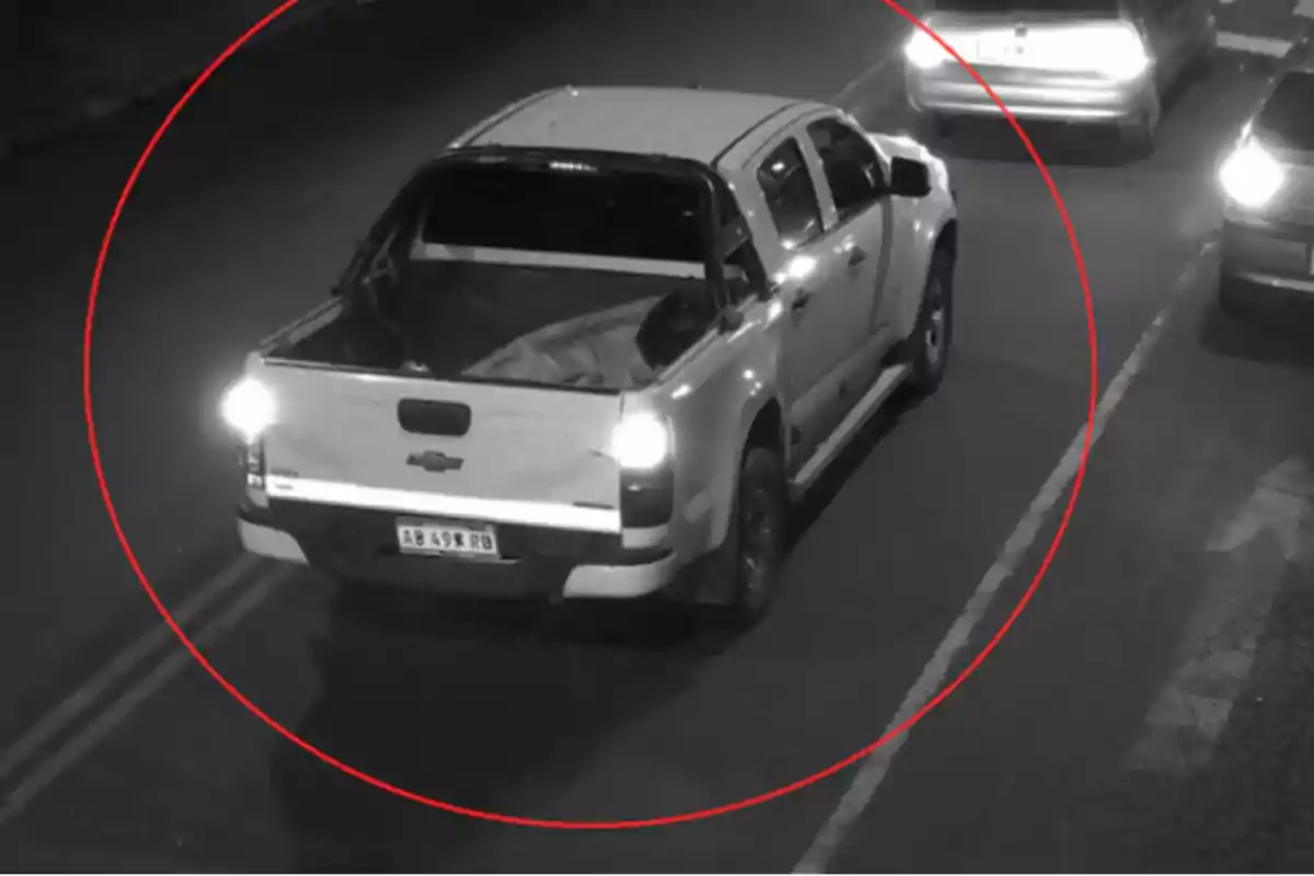 Camioneta blanca circulando de noche por una calle, resaltada con un círculo rojo Camioneta blanca circulando de noche por una calle, resaltada con un círculo rojo