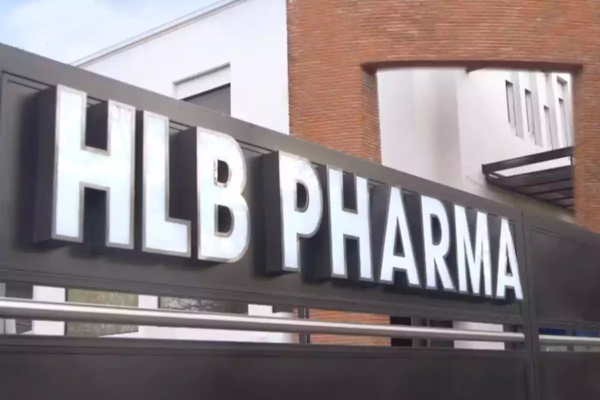 Letrero de HLB Pharma en la entrada de un edificio moderno con paredes blancas y detalles de ladrillo.