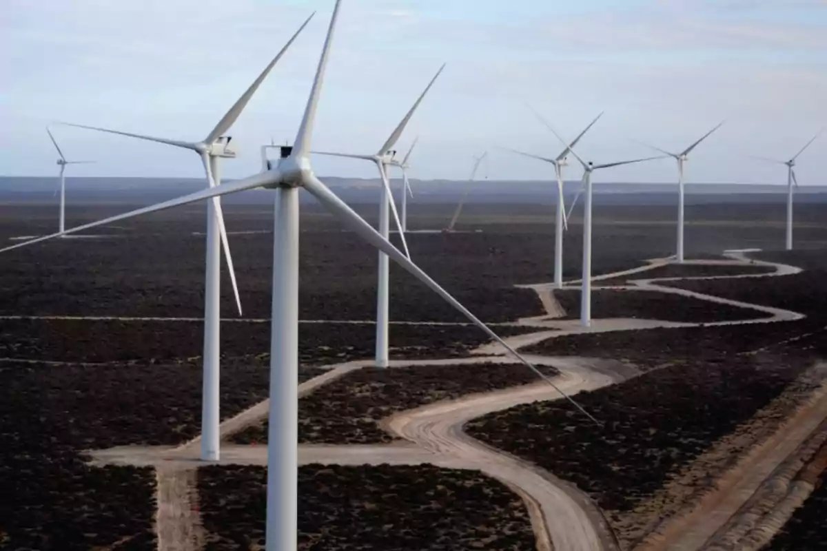 Varios aerogeneradores en un parque eólico sobre un terreno árido con un camino sinuoso Varios aerogeneradores en un parque eólico sobre un terreno árido con un camino sinuoso