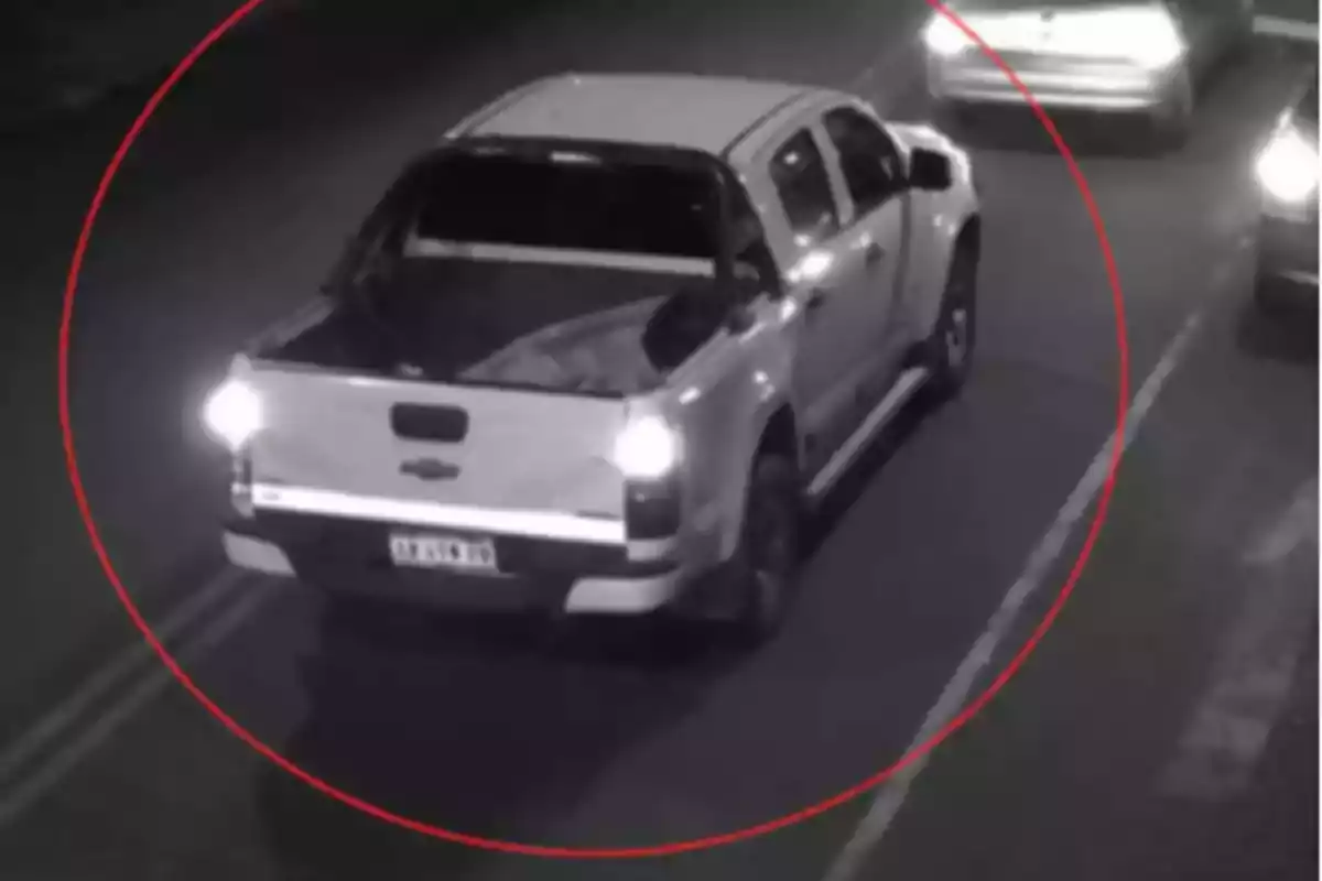 White pickup truck caught by a security camera driving at night on a street marked with a red circle White pickup truck caught by a security camera driving at night on a street marked with a red circle