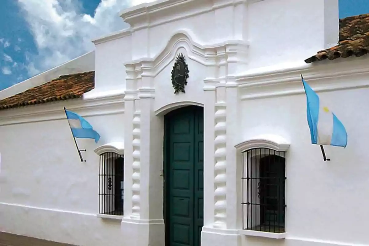 Facade of the Historic House of Tucumán with two Argentine flags waving on either side of the main door Facade of the Historic House of Tucumán with two Argentine flags waving on either side of the main door