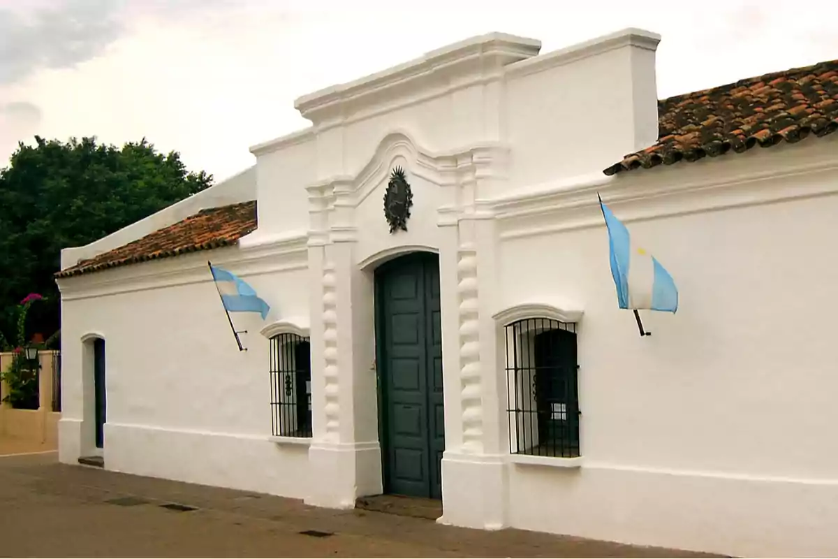 Facade of the Historic House of Tucumán with two Argentine flags waving on either side