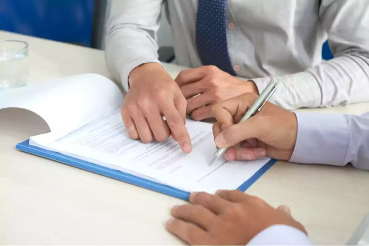 Two people review and sign a document on a table.