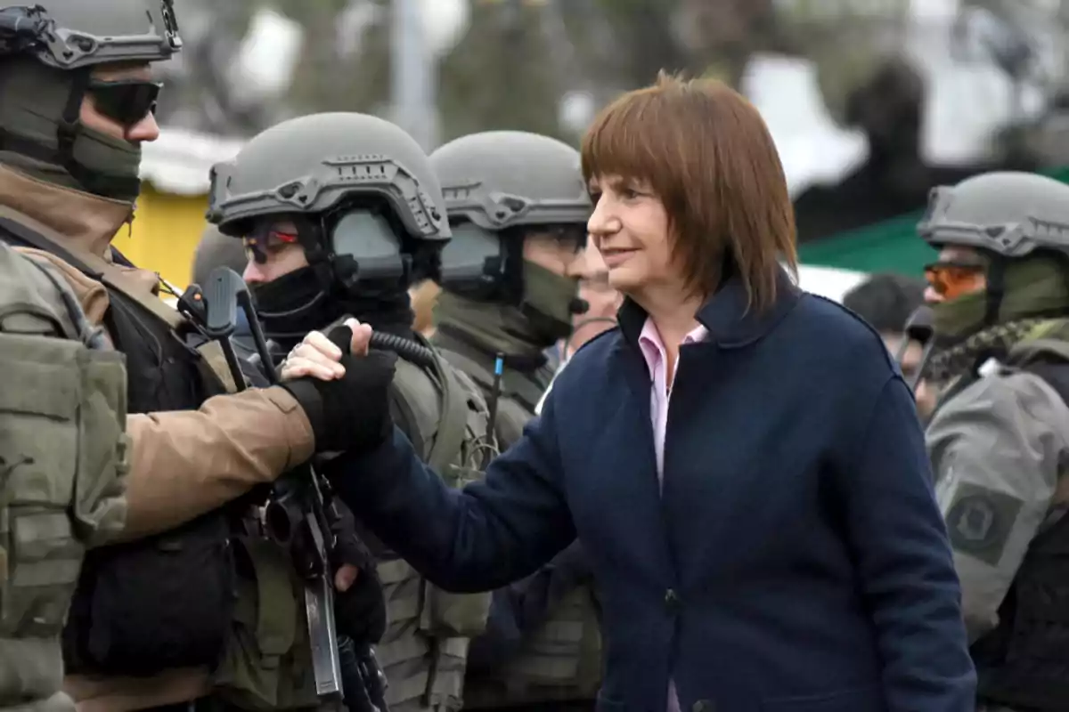 Woman wearing a blue coat greets a group of security officers in tactical uniforms and helmets. Woman wearing a blue coat greets a group of security officers in tactical uniforms and helmets.