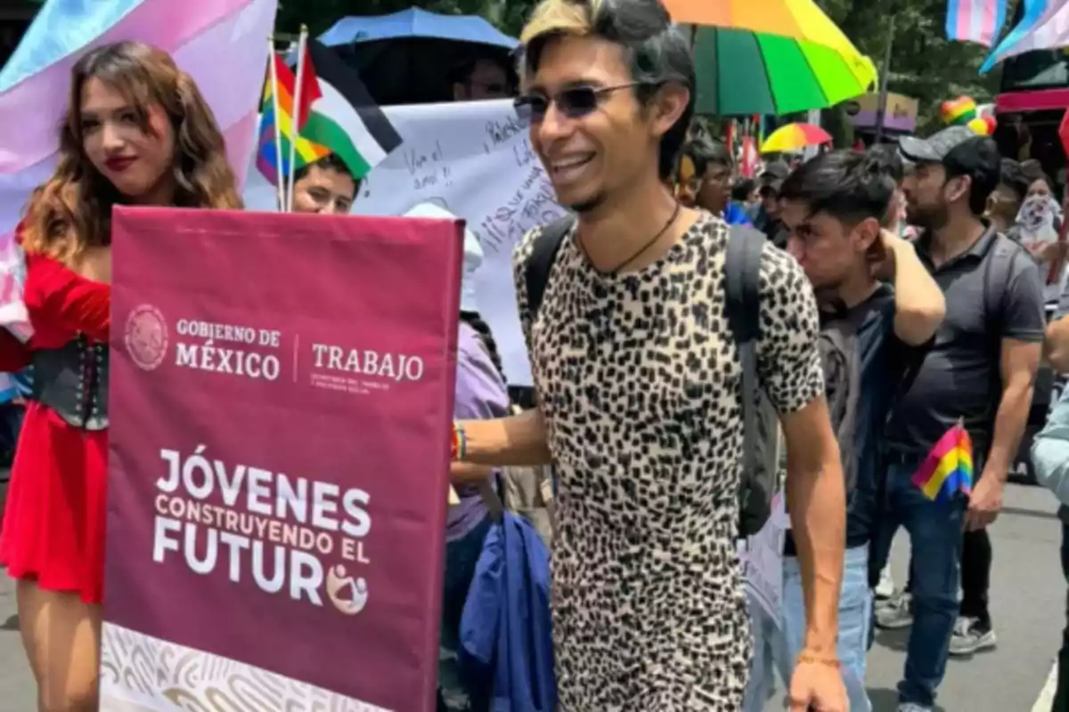 People marching in a parade with diversity flags and a sign for Jóvenes Construyendo el Futuro from the Government of Mexico