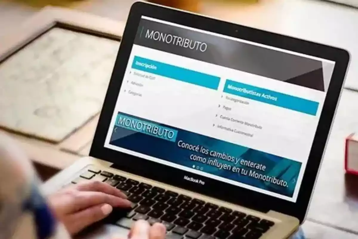 Persona usando una laptop que muestra en pantalla información sobre monotributo Persona usando una laptop que muestra en pantalla información sobre monotributo