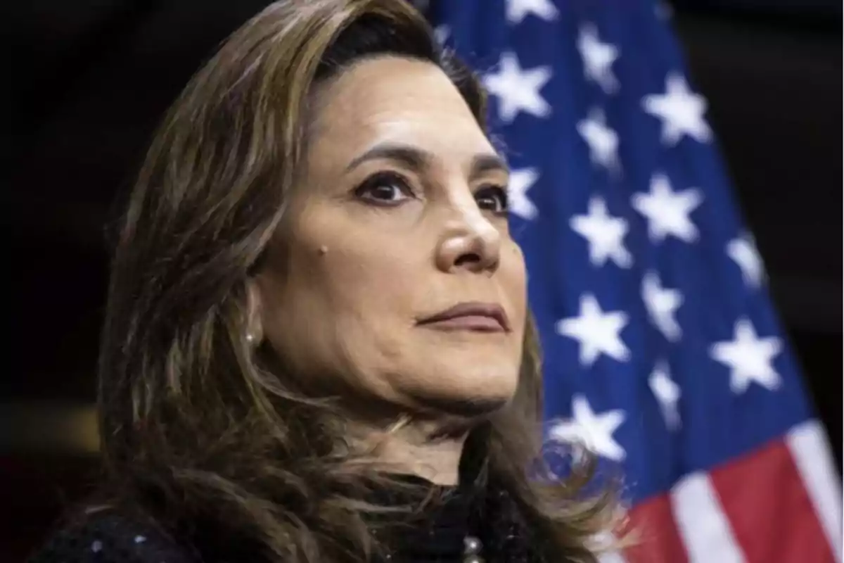 Brown-haired woman with a serious expression in front of a United States flag Brown-haired woman with a serious expression in front of a United States flag