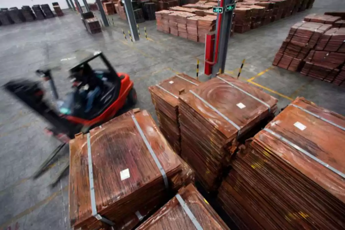 Montacargas en movimiento transportando láminas de cobre apiladas en el interior de una bodega industrial Montacargas en movimiento transportando láminas de cobre apiladas en el interior de una bodega industrial