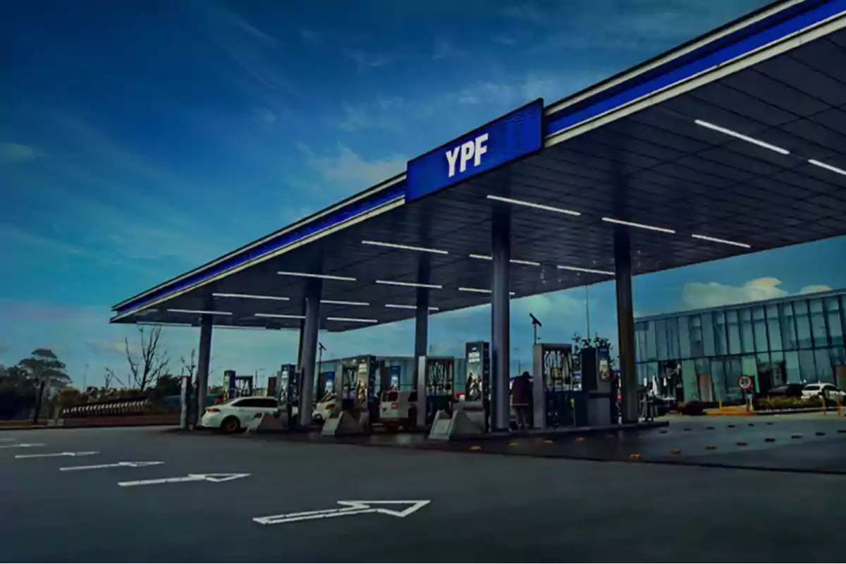 Estación de servicio YPF moderna con varios surtidores y autos cargando combustible bajo un cielo azul