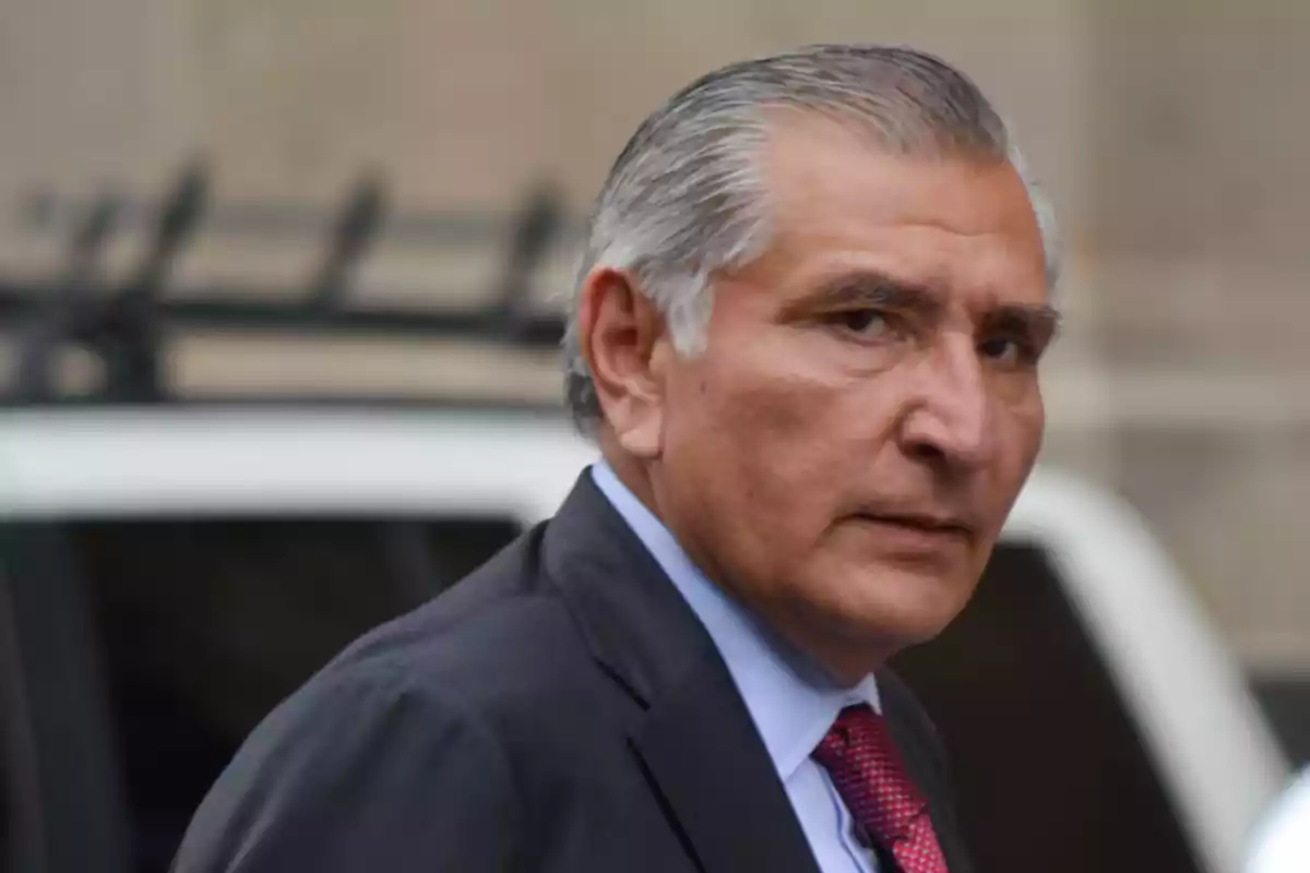 Gray-haired man in a dark suit with a red tie looking at the camera in an urban setting Gray-haired man in a dark suit with a red tie looking at the camera in an urban setting